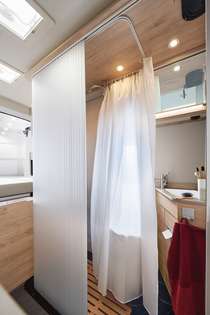 Cómoda ducha con una magnífica superficie de 87 × 47 cm. Puerta enrollable multifuncional: si se desea, se puede utilizar como sepa- ración entre el salón y el cuarto de aseo. Si se enrolla, se obtiene un gran espacio interior abierto.